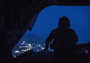 A CH-47 Chinook helicopter crew chief keeps watch during a flight over Kabul, Afghanistan,
